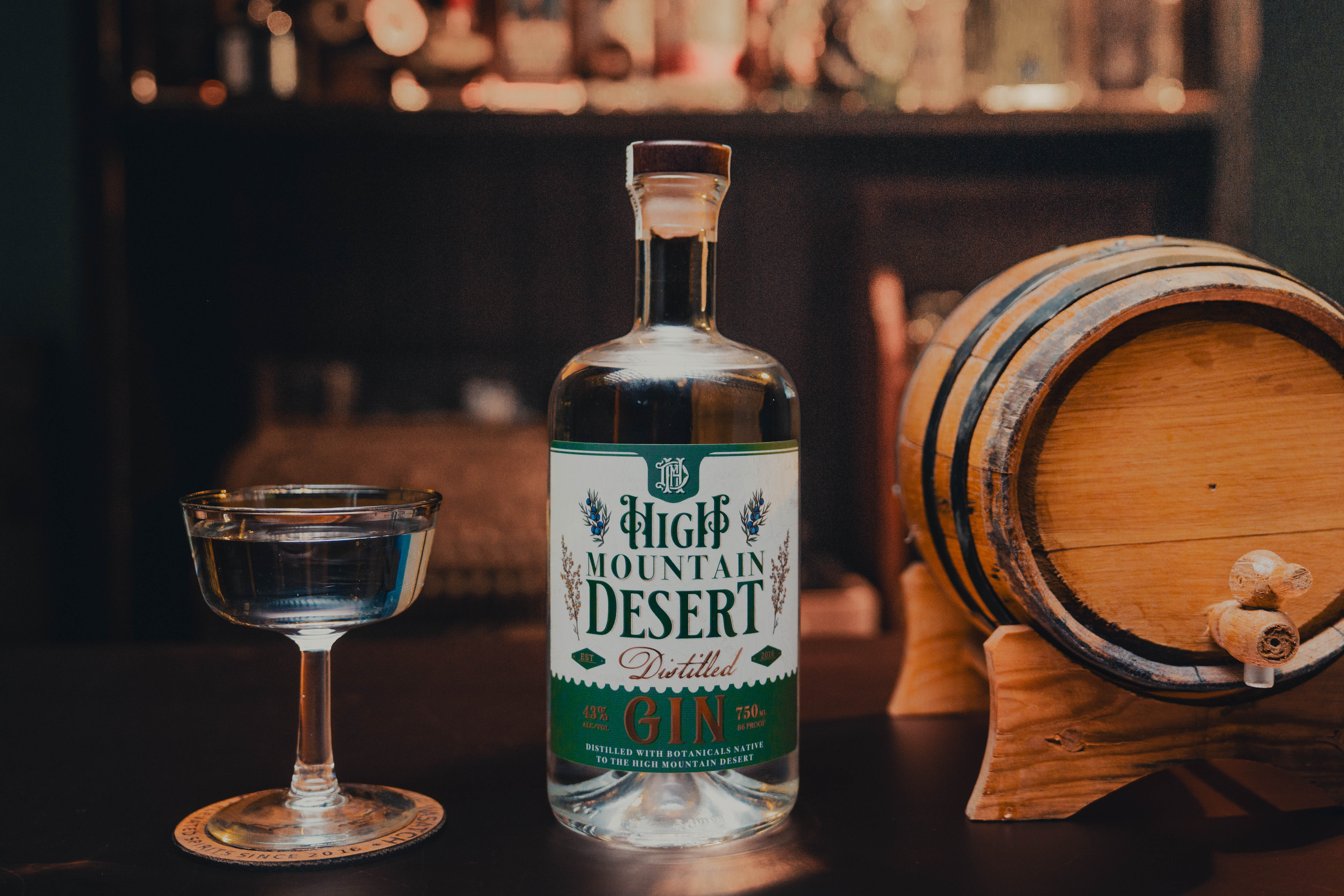 High Mountain Desert Gin Bottle - Professionally photographed. Sitting on the bartop with a glass to the left.